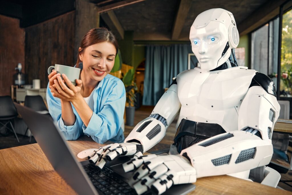 Robot and woman working on laptop in office
