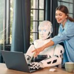 A woman and robot in front of a computer.