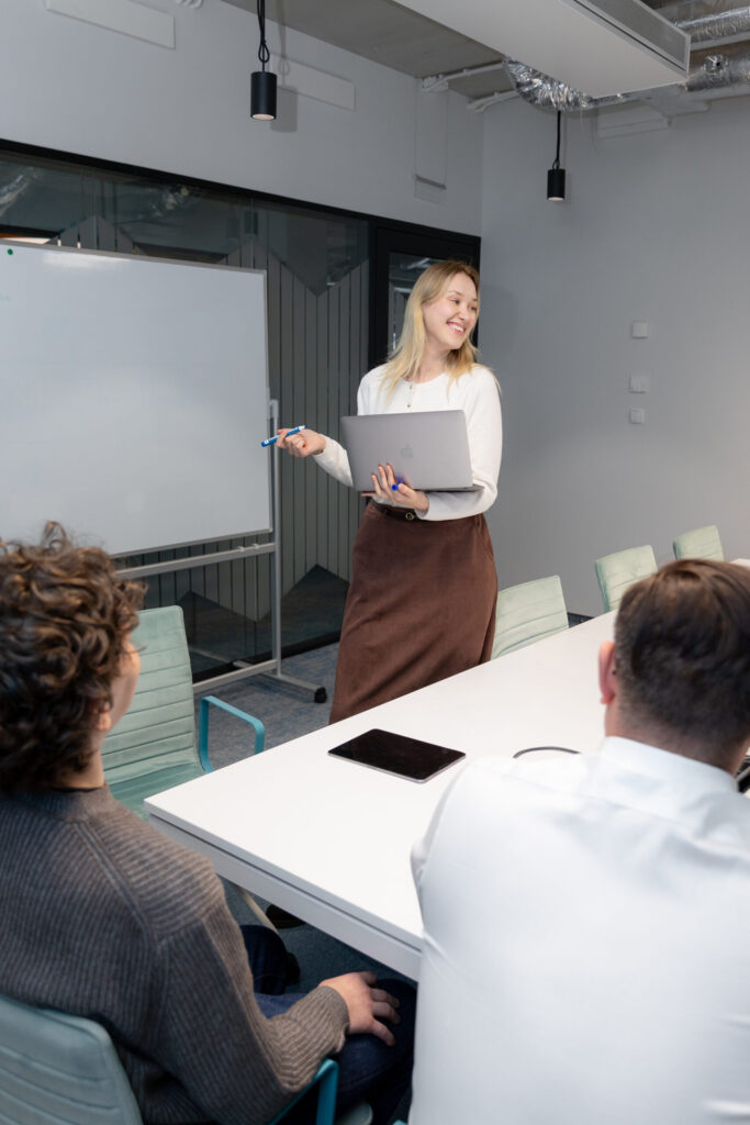 A picture of a Spyrosoft AdTech employee writing on a white board in front of a team of people.