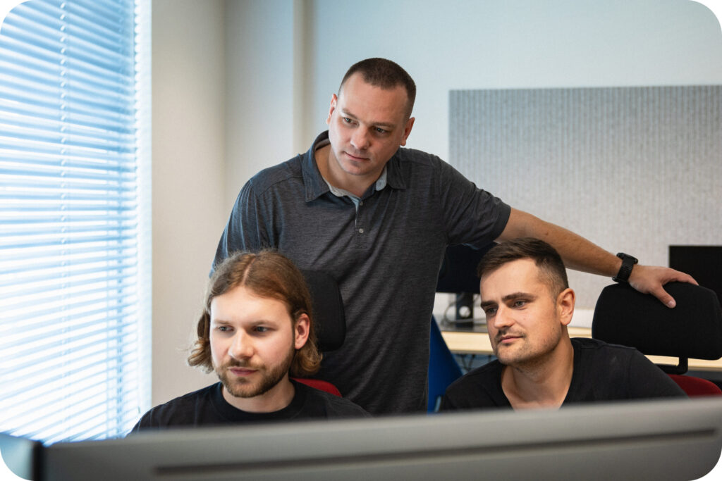 A photo of 3 Spyrosoft AdTech employees in front of a computer.
